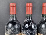 three bottles of red wine sitting on top of a wooden table