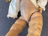 a wooden doll laying on the floor with a white shirt on