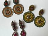 three pairs of earrings are sitting on a white surface