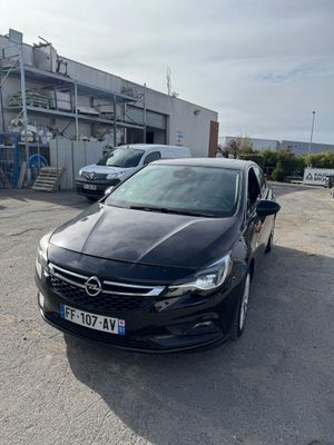 La voiture noire est garée sur le parking à côté de l'immeuble.