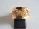 une photo d'une bague en or posée sur un socle noir