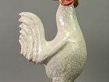une statue de coq blanc coiffée d'un chapeau rouge