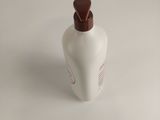 a white bottle with a brown top on a white table