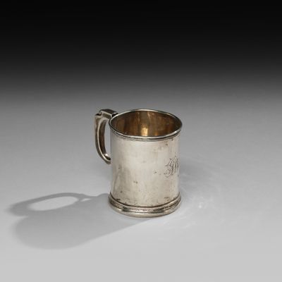 une vieille coupe en argent munie d'une anse, posée sur une surface blanche