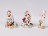 three porcelain figurines of children sitting on a bench with a dog