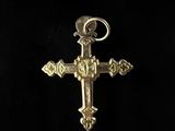 a gold cross with a bird on top of it on a black background