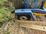 a blue and yellow tractor trailer parked next to a wooden fence