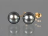 une paire de boucles d'oreilles en perles noires posées sur une surface réfléchissante