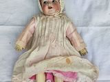 an old doll with a bonnet and dress laying on a white sheet