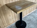a wooden table with a black metal base on the floor