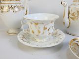 un service à thé blanc et doré posé sur une table blanche