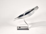 a metal sculpture of a bird on a stand