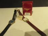 deux montres posées sur une table à côté d'une boîte rouge