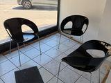 trois chaises noires dans une pièce dotée d'une grande fenêtre