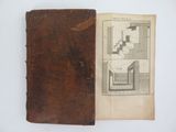 an old book sitting on top of a table next to a white wall
