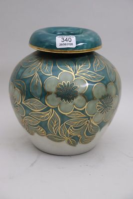 a blue and gold vase with a lid sitting on a table
