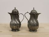 pair of antique silverplated teapots on a wooden table