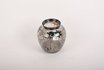 un vase en argent muni d'un couvercle noir, posé sur une surface blanche