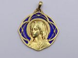 a close up of a gold and blue pendant with a woman ' s face
