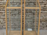 a pair of wooden and glass display cases with a brick wall in the background