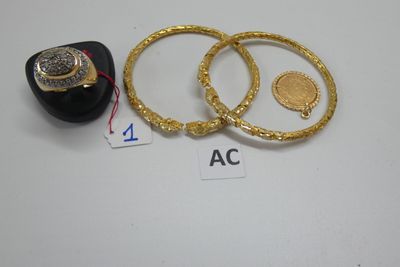 trois bagues en or et une bague avec une pièce de monnaie posées sur une table