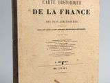 un vieux livre posé sur une table à côté d'un mur blanc