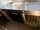 a stainless steel counter with a glass door in a kitchen