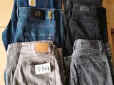 three pairs of men ' s jeans sitting on top of a cardboard box