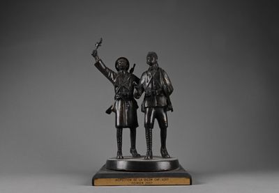 bronze statue of two men standing next to each other on a wooden base