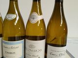 three bottles of white wine are lined up on a counter