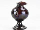 un vase noir orné d'un oiseau sur un fond blanc