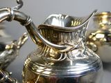a silver pitcher sitting on a table next to other silver pitchers