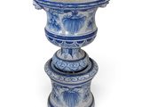 un grand vase bleu et blanc posé au sommet d'une pile de petits vases bleus et blancs