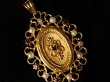 a close up of a gold pendant with pearls on a black background