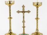 two gold candles and a cross on a white background