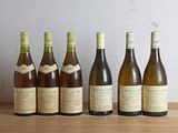 six bottles of wine are lined up on a wooden table
