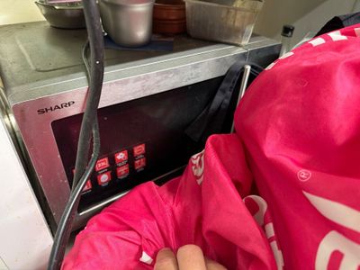 a person that is holding a bag in front of a microwave