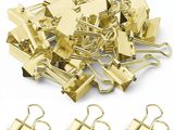 une pile de classeurs dorés et de trombones posée sur une surface blanche