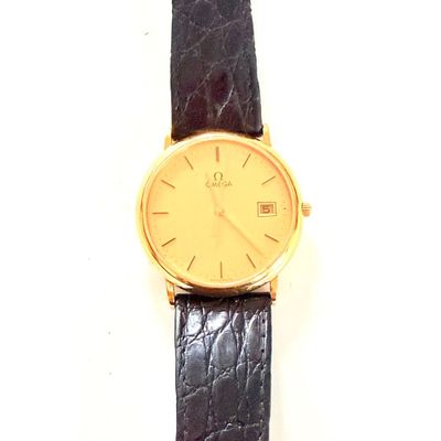 une montre en or avec un bracelet noir posée sur une surface blanche