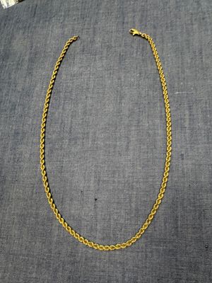 un collier à chaîne en or posé sur un tissu gris