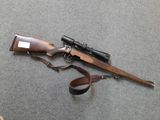 an old rifle with a scope and a sling on the ground