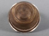 underside view of a silver cup with a brown lid on a gray surface