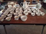de nombreuses tasses et soucoupes posées sur la table, prêtes à être utilisées