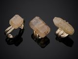 three gold rings with quartz stones on a black surface