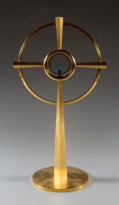 une image représentant une sculpture dorée représentant un objet circulaire posé sur un socle