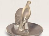 a silver plate with a bird on top of it on a white surface