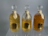 three bottles of perfume sitting on top of a clear shelf