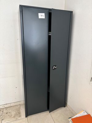 a black metal cabinet in a corner with a book on the floor