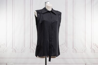 un t-shirt noir sans manches posé sur un mannequin devant un mur blanc