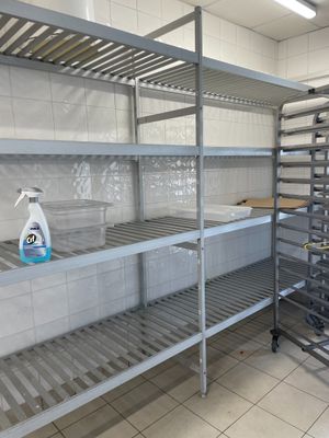 une étagère métallique au milieu d'une cuisine, sur laquelle sont posés de nombreux objets